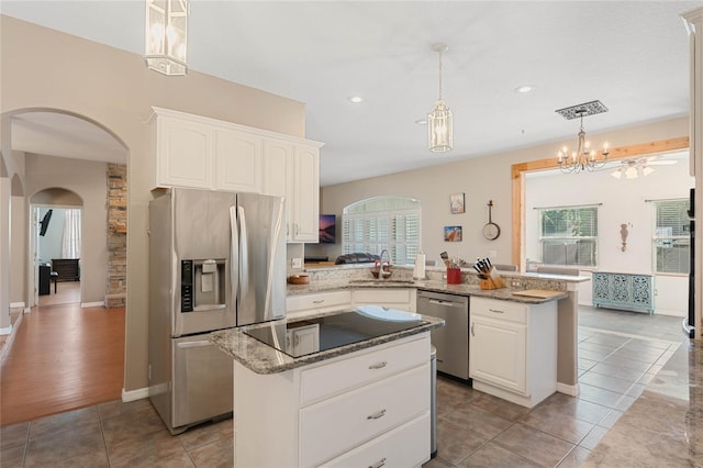 1031 Kings Hwy, Kissimmee, FL 34744 - kitchen with stainless steel appliances, a peninsula, arched walkways, white cabinets, and light stone counters