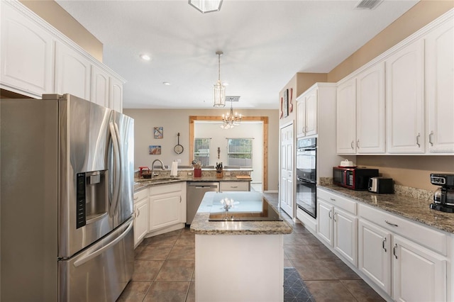 1031 Kings Hwy, Kissimmee, FL 34744 - kitchen with black appliances, a kitchen island, white cabinets, a chandelier, and a peninsula