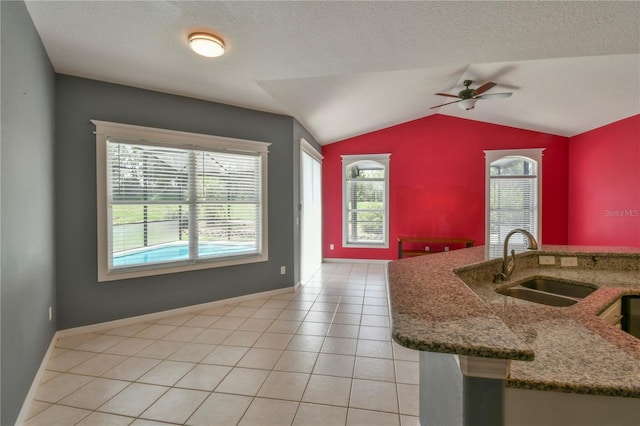 831 Corvina Dr, Davenport, FL 33897 - kitchen with a ceiling fan, vaulted ceiling, stone counters, and light tile patterned floors