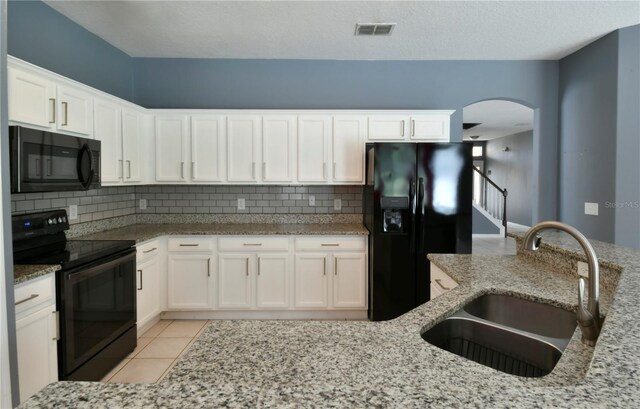 831 Corvina Dr, Davenport, FL 33897 - kitchen featuring black appliances, white cabinetry, decorative backsplash, and light stone countertops