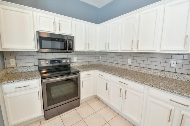 831 Corvina Dr, Davenport, FL 33897 - kitchen featuring appliances with stainless steel finishes, light tile patterned floors, white cabinetry, backsplash, and light stone countertops