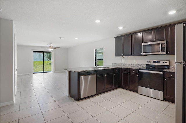 257 Fig Ct, Kissimmee, FL 34759 - kitchen with stainless steel appliances, a ceiling fan, a peninsula, open floor plan, and light stone countertops