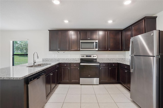 257 Fig Ct, Kissimmee, FL 34759 - kitchen featuring stainless steel appliances, a peninsula, light stone counters, dark brown cabinets, and light tile patterned floors