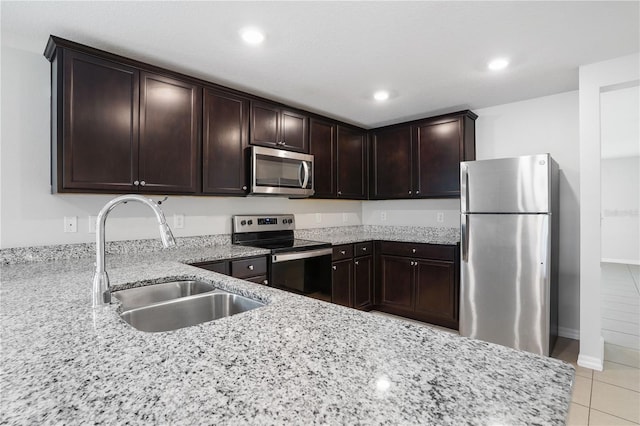 257 Fig Ct, Kissimmee, FL 34759 - kitchen with stainless steel appliances, light stone counters, dark brown cabinets, light tile patterned floors, and recessed lighting