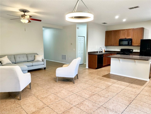 535 Aeolian Dr, New Smyrna Beach, FL 32168 - kitchen with black appliances, dark countertops, open floor plan, light tile patterned floors, and ceiling fan