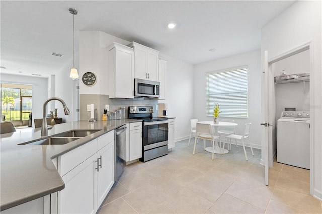3123 Camden Way, Davenport, FL 33837 - kitchen featuring appliances with stainless steel finishes, washer / dryer, a sink, tasteful backsplash, and white cabinetry