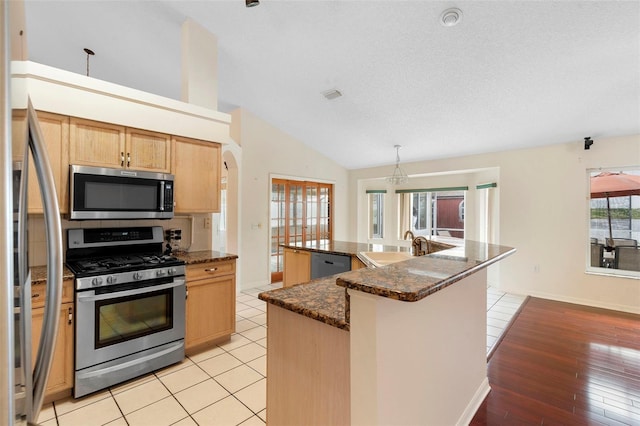 40 Hollow Pine Dr, Debary, FL 32713 - kitchen with stainless steel appliances, lofted ceiling, a large island, light brown cabinets, and arched walkways