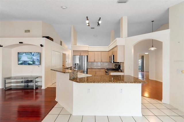 40 Hollow Pine Dr, Debary, FL 32713 - kitchen featuring appliances with stainless steel finishes, arched walkways, light wood-style floors, dark stone counters, and high vaulted ceiling