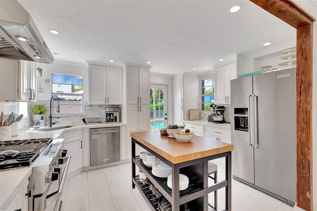 322 Cornell Dr, Lake Worth, FL 33460 - kitchen with stainless steel appliances, extractor fan, decorative backsplash, crown molding, and white cabinets