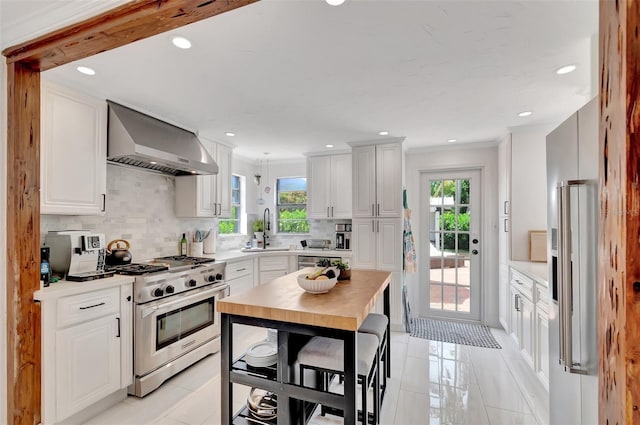 322 Cornell Dr, Lake Worth, FL 33460 - kitchen featuring high end appliances, wall chimney exhaust hood, a sink, plenty of natural light, and recessed lighting