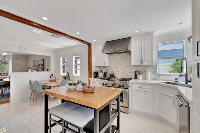 322 Cornell Dr, Lake Worth, FL 33460 - kitchen featuring wall chimney range hood, appliances with stainless steel finishes, a sink, light countertops, and crown molding