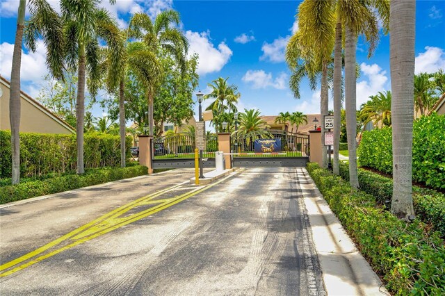19367 NW 13th St, Pembroke Pines, FL 33029 - view of asphalt street featuring a gate, traffic signs, street lights, a gated entry, and curbs