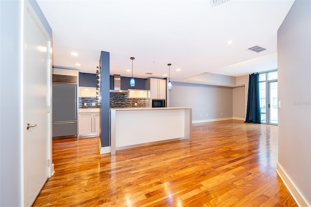 260 S Osceola Ave Unit 710, Orlando, FL 32801 - kitchen featuring built in appliances, wall chimney exhaust hood, tasteful backsplash, light wood finished floors, and decorative light fixtures