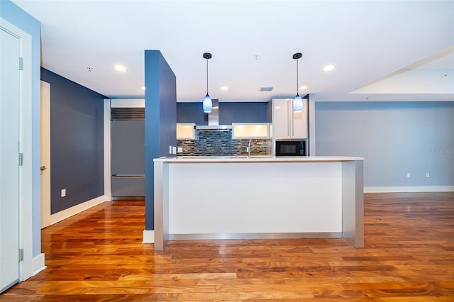 260 S Osceola Ave Unit 710, Orlando, FL 32801 - kitchen featuring black microwave, wall chimney range hood, built in fridge, tasteful backsplash, and wood finished floors