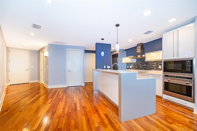 260 S Osceola Ave Unit 710, Orlando, FL 32801 - kitchen featuring built in appliances, light countertops, backsplash, white cabinetry, and hanging light fixtures