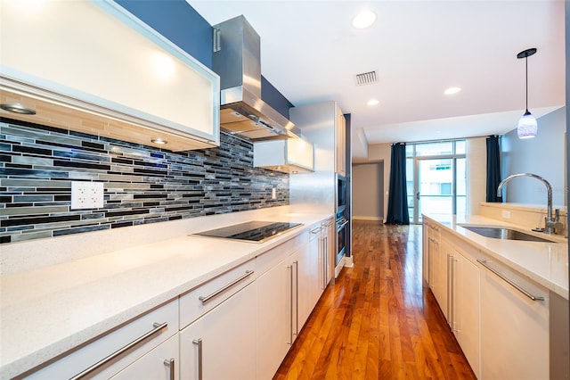 260 S Osceola Ave Unit 710, Orlando, FL 32801 - kitchen featuring ventilation hood, black electric cooktop, decorative backsplash, hanging light fixtures, and light wood-style floors