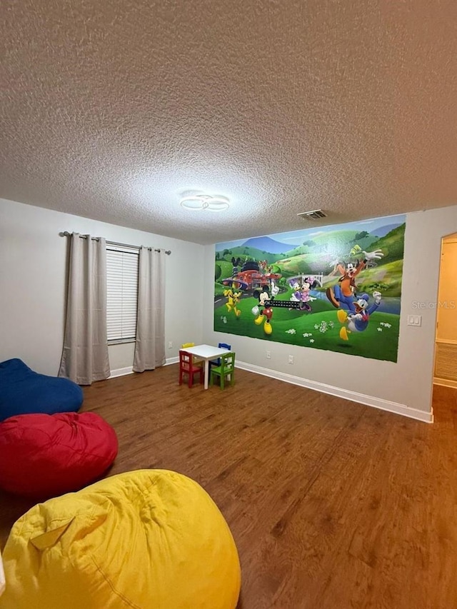 8894 Candy Palm Rd, Kissimmee, FL 34747 - rec room with wood finished floors, a textured ceiling, and baseboards