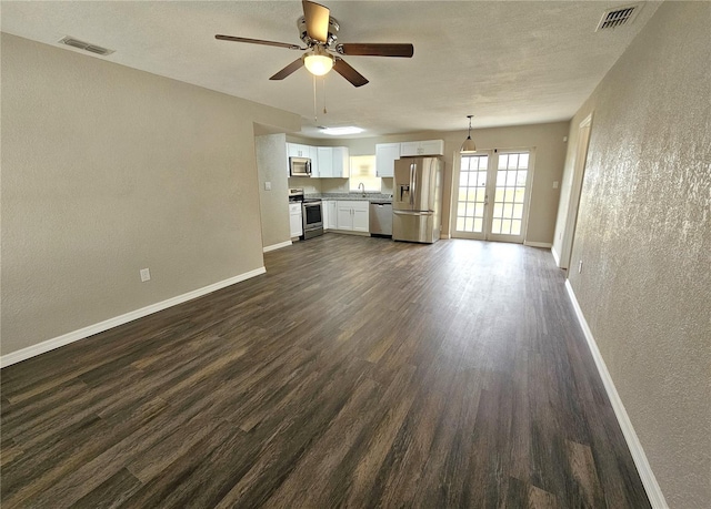 unfurnished living room with a textured wall, a ceiling fan, baseboards, dark wood-style floors, and a sink
