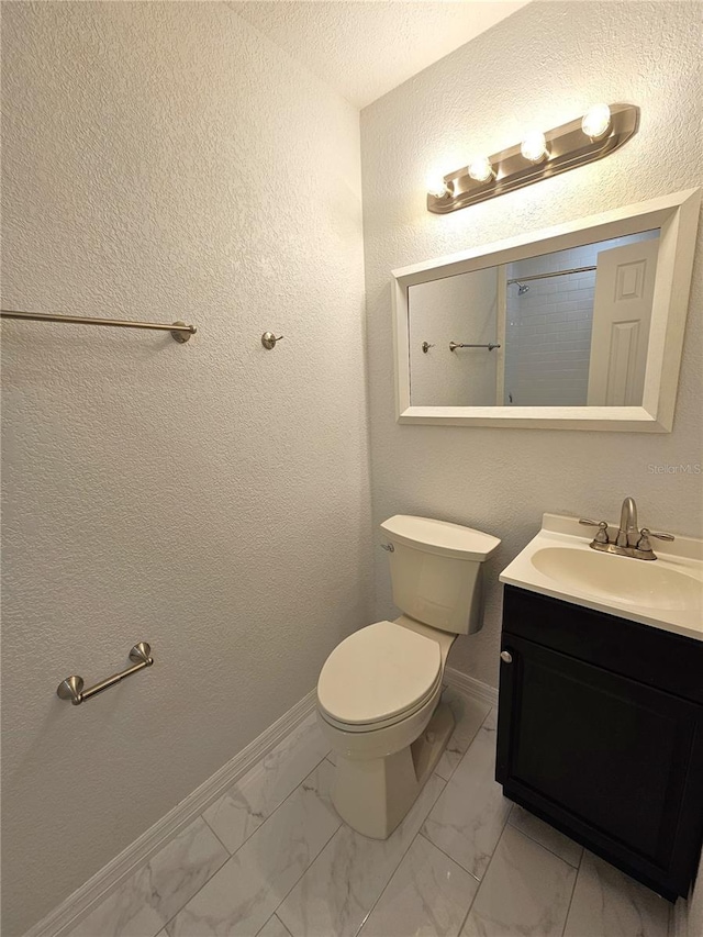 bathroom featuring vanity, marble finish floors, toilet, and baseboards