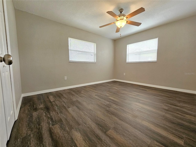 unfurnished room with plenty of natural light, dark wood-style floors, and baseboards