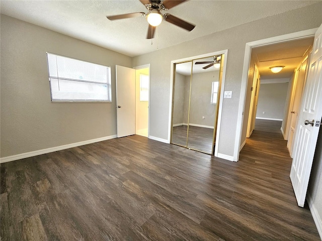 unfurnished bedroom featuring dark wood-style floors, multiple windows, a closet, and a textured ceiling