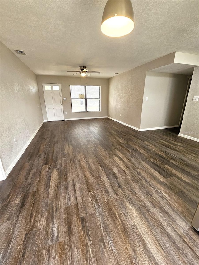 spare room with a textured wall, a textured ceiling, dark wood-style flooring, a ceiling fan, and baseboards