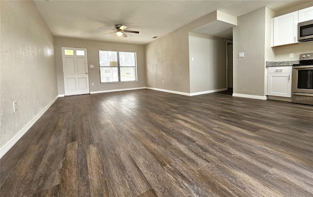 unfurnished living room with a textured wall, dark wood-style floors, ceiling fan, and baseboards
