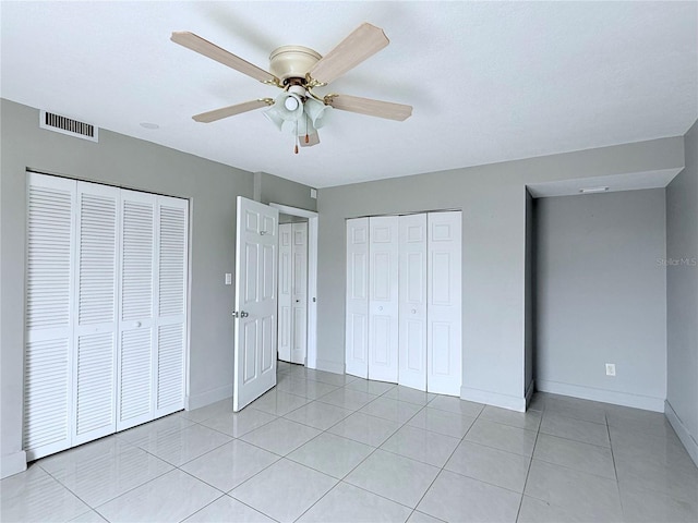 250 N Banana River Dr Unit H11, Merritt Island, FL 32952 - unfurnished bedroom with two closets, baseboards, light tile patterned floors, and ceiling fan