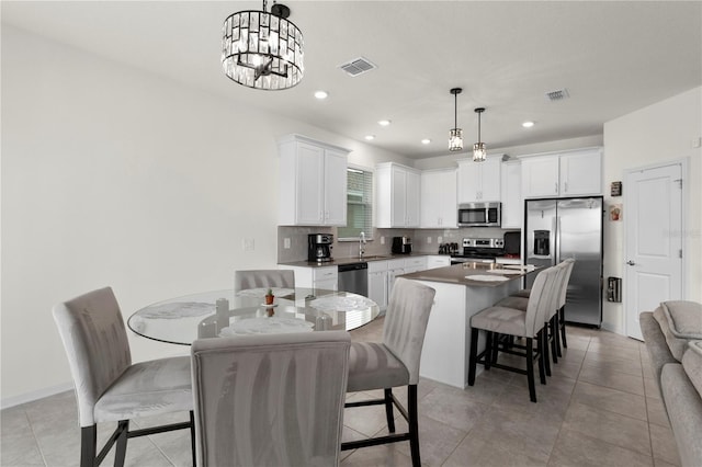 884 Laurel View Way, Groveland, FL 34736 - kitchen featuring appliances with stainless steel finishes, a kitchen bar, tasteful backsplash, white cabinets, and hanging light fixtures