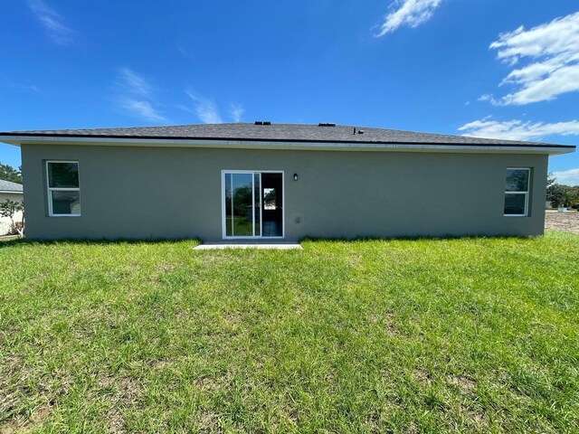 104 W Gondolier Pl, Citrus Springs, FL 34434 - rear view of property with stucco siding and a yard
