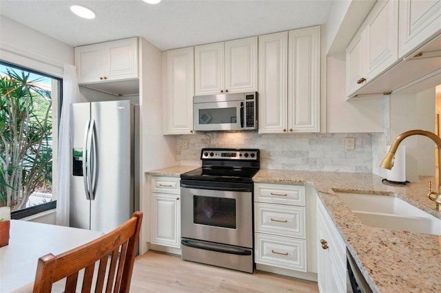 6218 Palma Del Mar Blvd S Unit 103, Saint Petersburg, FL 33715 - kitchen with stainless steel appliances, a sink, backsplash, white cabinetry, and light wood-style flooring