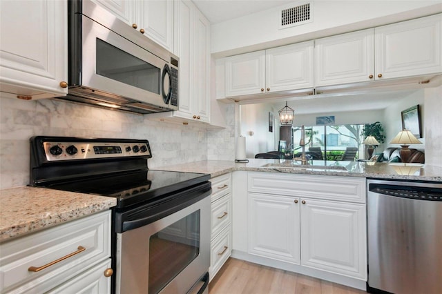 6218 Palma Del Mar Blvd S Unit 103, Saint Petersburg, FL 33715 - kitchen with appliances with stainless steel finishes, light stone counters, white cabinets, tasteful backsplash, and light wood-style floors