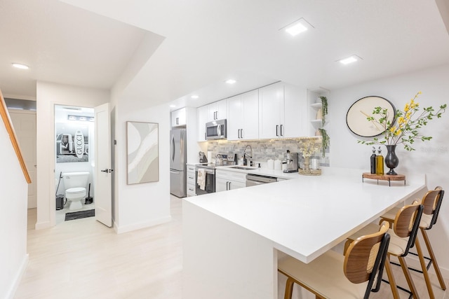 701 S Atlantic Ave Unit Ut21, New Smyrna Beach, FL 32169 - kitchen with stainless steel appliances, open shelves, a breakfast bar, baseboards, and decorative backsplash