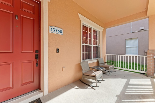 13768 Bluebird Pond Rd, Windermere, FL 34786 - doorway to property featuring covered porch and stucco siding