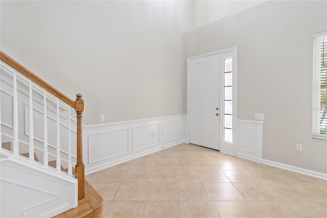 13519 Bicton Ln, Windermere, FL 34786 - entrance foyer featuring stairway, light tile patterned floors, a decorative wall, wainscoting, and a high ceiling