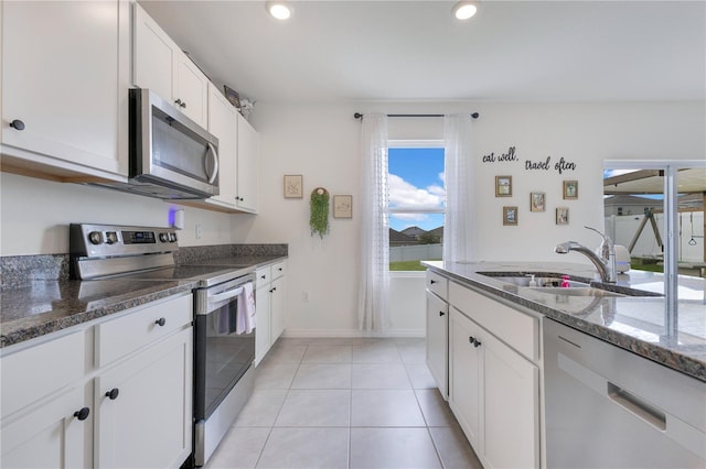 1854 Juneberry St, Clermont, FL 34715 - kitchen with stainless steel appliances, dark stone counters, white cabinetry, light tile patterned flooring, and recessed lighting