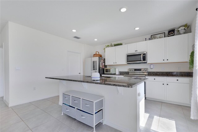 1854 Juneberry St, Clermont, FL 34715 - kitchen featuring appliances with stainless steel finishes, white cabinets, light tile patterned floors, dark stone counters, and recessed lighting