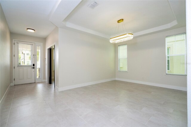 5161 Dove Tree St, Orlando, FL 32811 - spare room with a tray ceiling, a chandelier, and light tile patterned floors