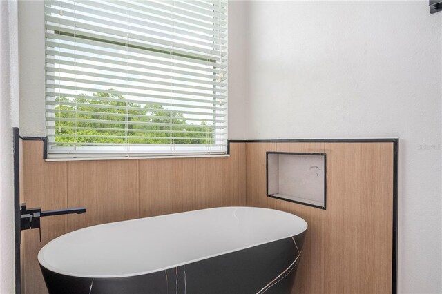 5161 Dove Tree St, Orlando, FL 32811 - bathroom featuring a wainscoted wall, a freestanding bath, healthy amount of natural light, and wood walls