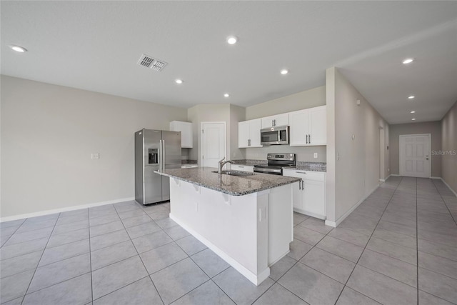 489 Panaro Ln, Haines City, FL 33844 - kitchen with stainless steel appliances, stone countertops, an island with sink, light tile patterned flooring, and white cabinetry