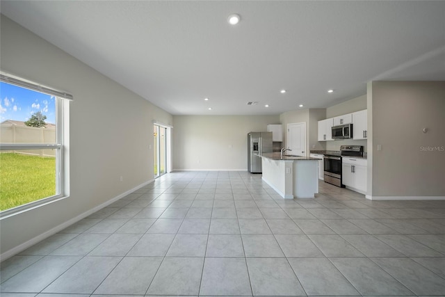 489 Panaro Ln, Haines City, FL 33844 - kitchen with stainless steel appliances, open floor plan, an island with sink, baseboards, and a sink