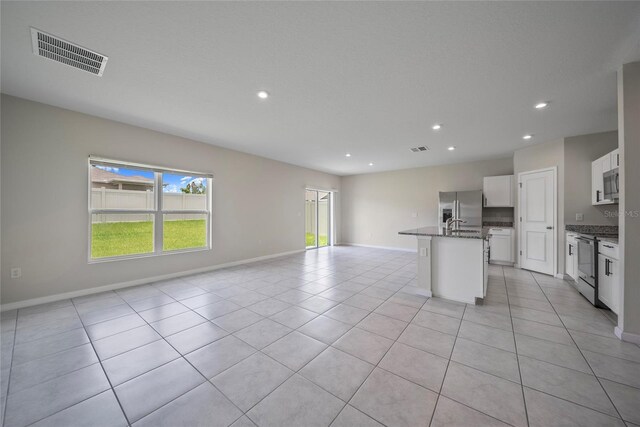 489 Panaro Ln, Haines City, FL 33844 - kitchen featuring appliances with stainless steel finishes, open floor plan, a center island with sink, recessed lighting, and stone countertops