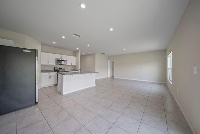489 Panaro Ln, Haines City, FL 33844 - kitchen with stainless steel appliances, open floor plan, an island with sink, white cabinetry, and light tile patterned flooring