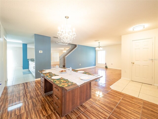 8330 Lainie Ln, Orlando, FL 32818 - kitchen featuring light tile patterned floors, a chandelier, a center island, and decorative light fixtures