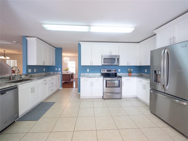 8330 Lainie Ln, Orlando, FL 32818 - kitchen featuring appliances with stainless steel finishes, a chandelier, light stone countertops, and white cabinets