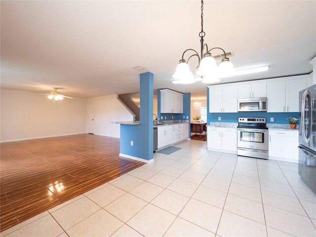 8330 Lainie Ln, Orlando, FL 32818 - kitchen featuring appliances with stainless steel finishes, open floor plan, a chandelier, light tile patterned flooring, and white cabinetry