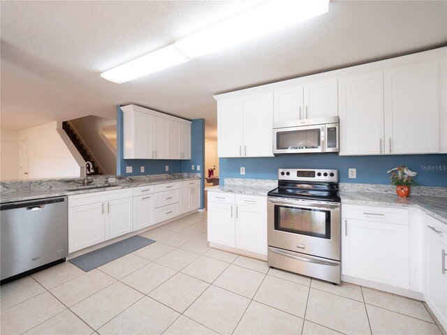 8330 Lainie Ln, Orlando, FL 32818 - kitchen with appliances with stainless steel finishes, white cabinetry, light tile patterned floors, and light stone countertops