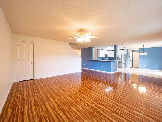 8330 Lainie Ln, Orlando, FL 32818 - unfurnished living room with a ceiling fan, a textured ceiling, and a chandelier