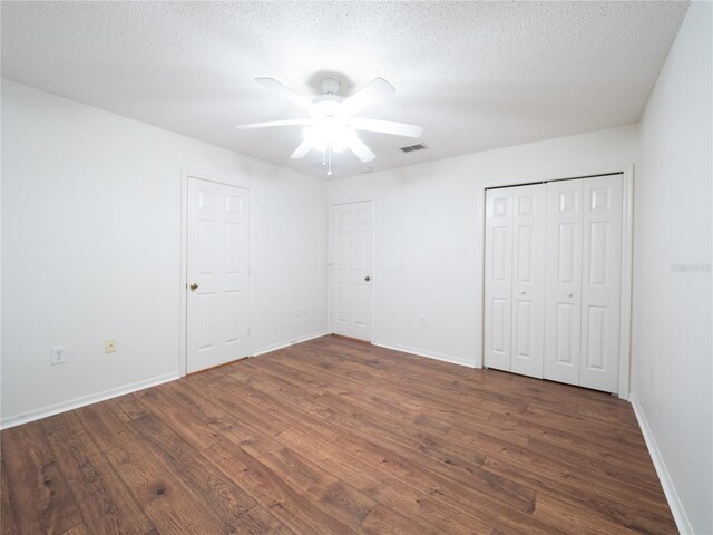 8330 Lainie Ln, Orlando, FL 32818 - unfurnished bedroom featuring dark wood-type flooring, multiple closets, a ceiling fan, and a textured ceiling