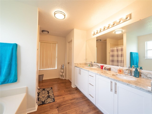 8330 Lainie Ln, Orlando, FL 32818 - full bathroom with double vanity, wood finished floors, a bathtub, a textured ceiling, and a shower with shower curtain